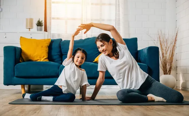 A mother coaches her little daughter in yoga creating a family bond filled with happiness relaxation and togetherness.